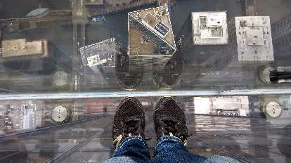 black shoes, looking down at buildings, on top of buildings, clear glass