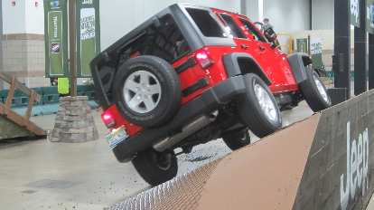 A red 2015 Jeep Wrangler on the sideways incline of the Jeep obstacle course at the 2015 Denver Auto Show. red 2015 Jeep Wrangler, sideways incline, 2015 Denver Auto Show