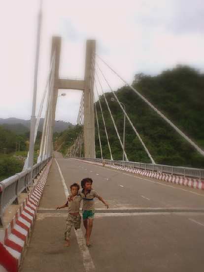 Kids on a bridge over a river.