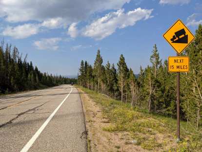 Yellow sign that says "Downhill next 15 miles" heading east from Cameron Pass on Highway 14 in Colorado