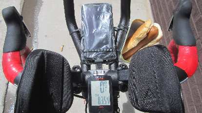 The cockpit of the Super Bike. I used a SPAM can as a snack box, and it was the perfect size for a hot dog. handlebars, red handlebar tape, aerobars, phone, cycle computer, hot dog