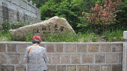 Older woman in front of a stone rock.