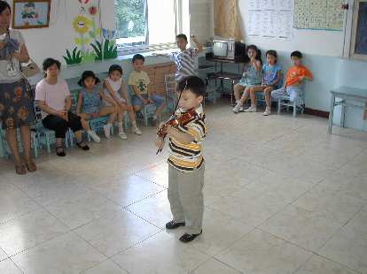 A kindergarten class with a boy playing the violin.