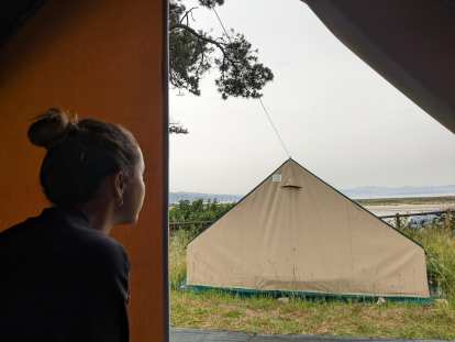 Andrea looking out of the tent towards Rodas Beach and the Atlantic Ocean on a cloudy morning.
