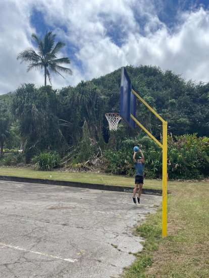 Felix shooting a flat blue basketball at Laupahoehoe.