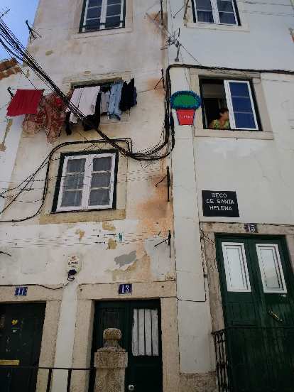 A woman peering out the window of a townhome in Alfama. A woman peering out the window of a townhome in Alfama.