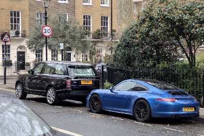 A black Land Rover Discovery and Blue Porsche 911 in a neighborhood north of Hyde Park. A black Land Rover Discovery and Blue Porsche 911 in a neighborhood north of Hyde Park.