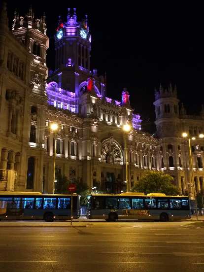 Buses in front of Palacio de Cibeles at night.