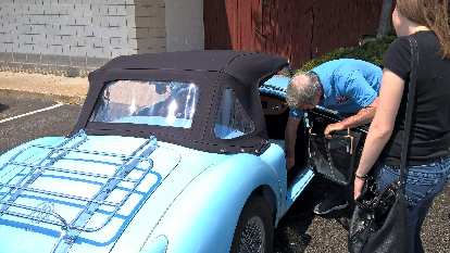 Mike Jacobsen shows Maureen the side curtains on his light blue MGA roadster.