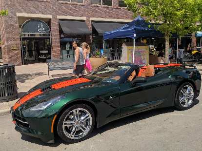A green C6 Corvette Convertible with orange racing stripes.