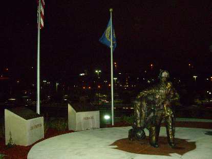 Statue near the Quest Center, with the lights of downtown Omaha beyond.