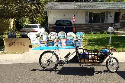 A cargo bike in front of an art sale.