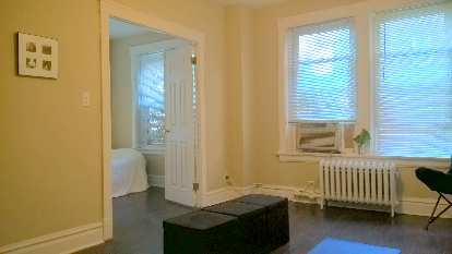 minimalist living room, black ottomans, black folding chair, silver can of green leaves, picture frame, blue yoga mat