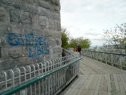 Photo: brick building with Quebec Libre painted in blue letters by wooden pathway