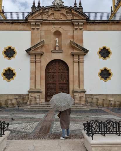 Andrea holding an umbrella and facing a door near the Plaza del Socorro.