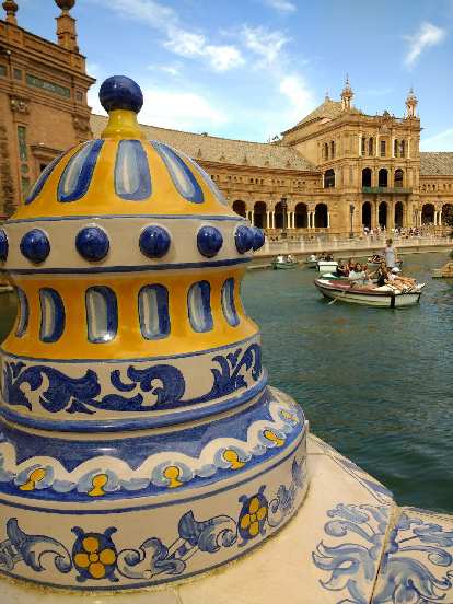 Blue, yellow, and white art sculpture, and canoes in the canal, by the Plaza de España in Seville, Spain.