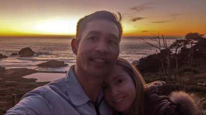 Felix and Andrea with the Sutro Baths and a sunset over the Pacific Ocean behind.