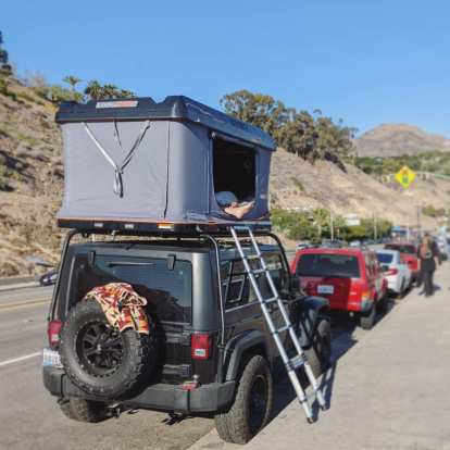 A Roofnest rooftop tent on top of a Jeep Wrangler with a ladder in Malibu.