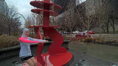 Maureen doing chair pose with a red statue in Citygarden. Maureen, chair pose, red statue, Citygarden, red Audi TT coupe