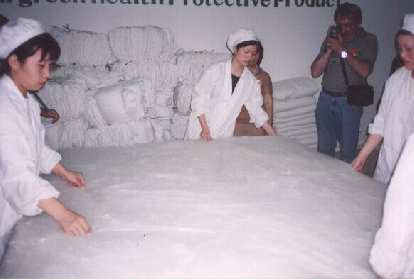 Factory workers creating a silk comforter by hand.