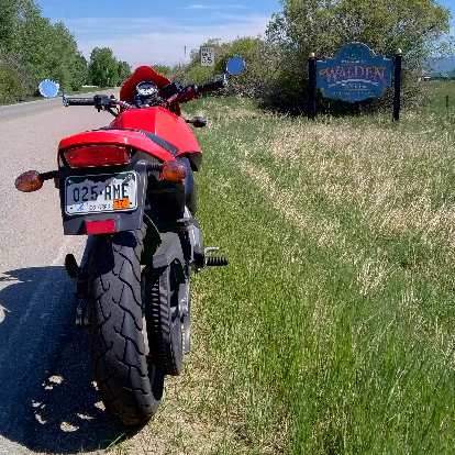 Felix Wong's red 2003 Buell Blast in front of a sign in Walden, Colorado.