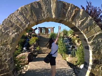 Maureen reaching for the top of the arch at The Rock Garden.