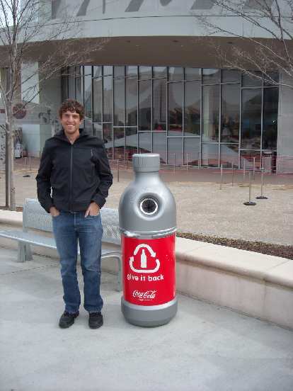 Dan next to a bottle-shapped recycling repository.