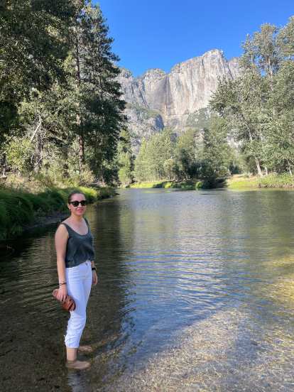 Andrea standing in the Merced River, with the Three Brothers rock formation in the background.