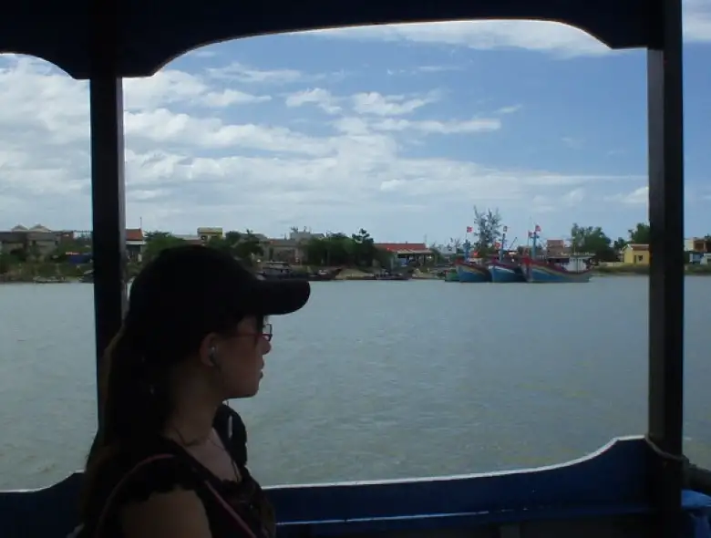 Vietnamese girl listens to MP3s on her Sony Ericson cell phone while looking out the boat from My Son to Hoi An.