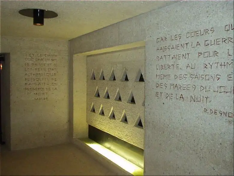 The triangles are representative of the identification patches inmates were forced to wear.  Just to the right of this, above the exit, are the words, 