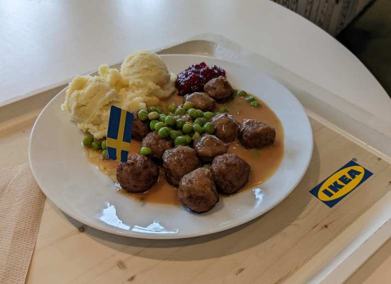 white plate with IKEA Swedish meatballs, mash potatoes, peas, gravy, and mini Swedish flag