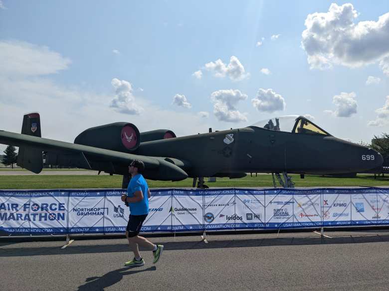 A marathoner runs by a rescue plane in the 2022 Air Force Marathon.