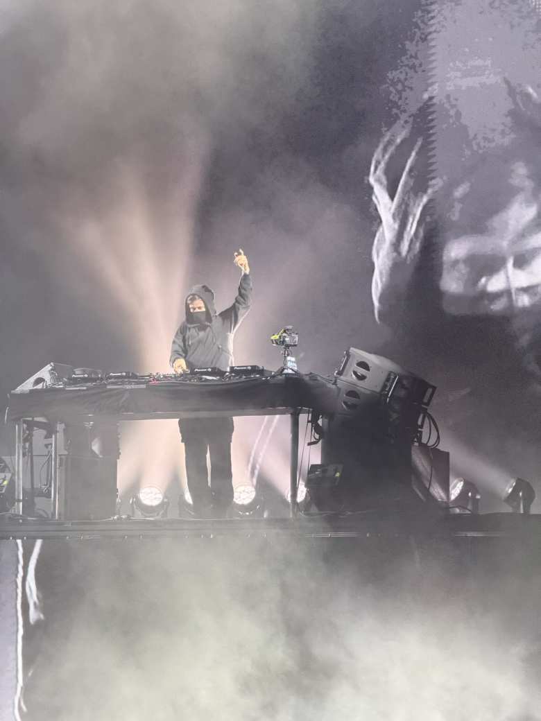 Alan Walker turns a dial as he raises his left hand.