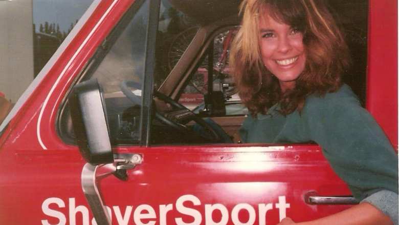 Alexandra Paul as Becky, seated inside the red Ford van emblazoned with the ShaverSport logo, in American Flyers.