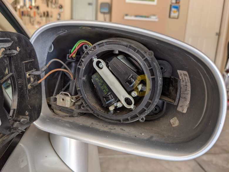 The right mirror assembly of a 2001 Audi TT. Circled in yellow is where the white plastic motor "arm" had become separated from the black ball-and-socket joint. After reconnecting it, the power mirror worked again.