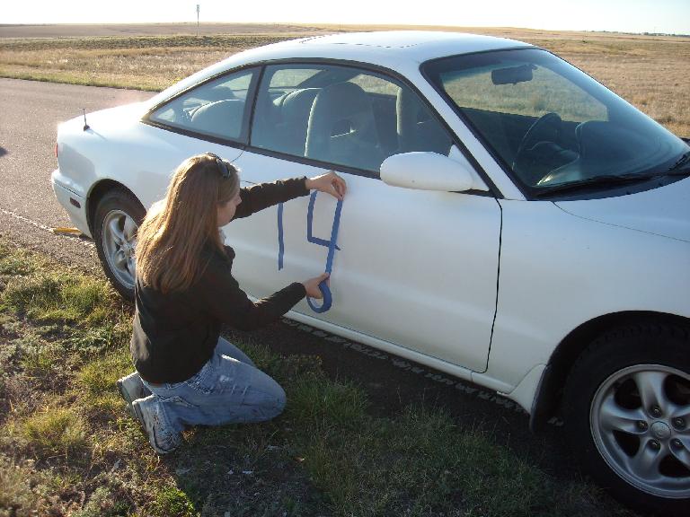 Kelly applying numbers to the right side of her car.
