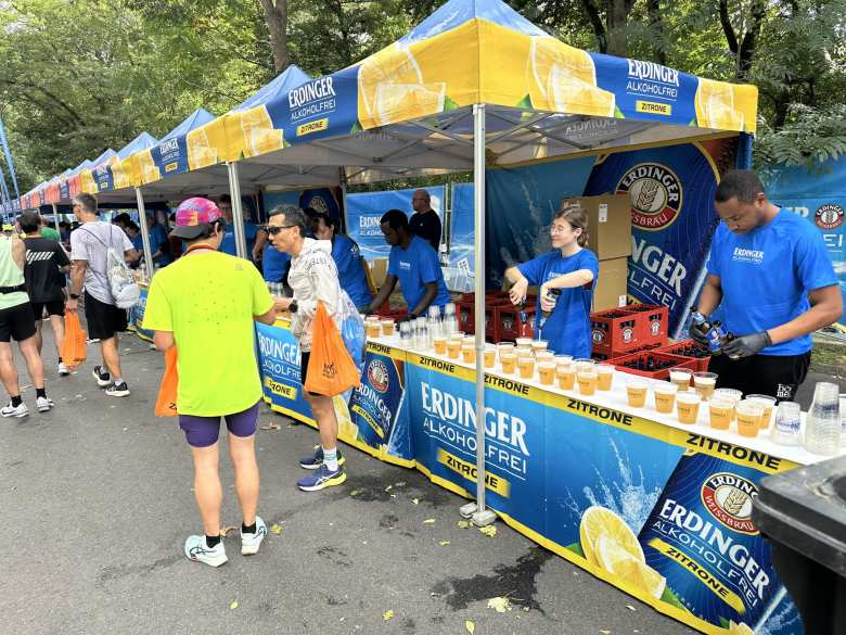 A young woman pouring Erdinger alcohol-free beer into plastic cups at a booth at the Berlin Marathon