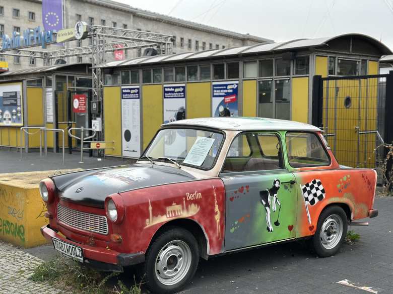 A Trabant painted in red, grey, green, orange, and white.