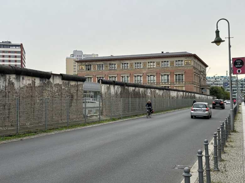 A cyclist rides by historical remnants of the Berlin Wall.