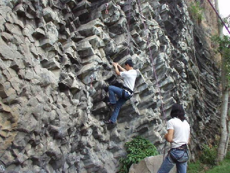 Felix Wong gives the 5.11a a try while Caesar belays.