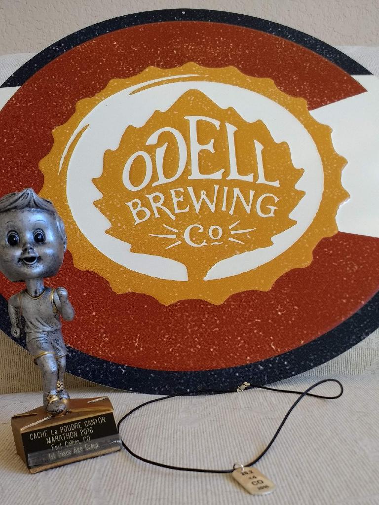 grey bobblehead figure trophy, Odell Brewing Co. placard, necklace with sterling silver pendant