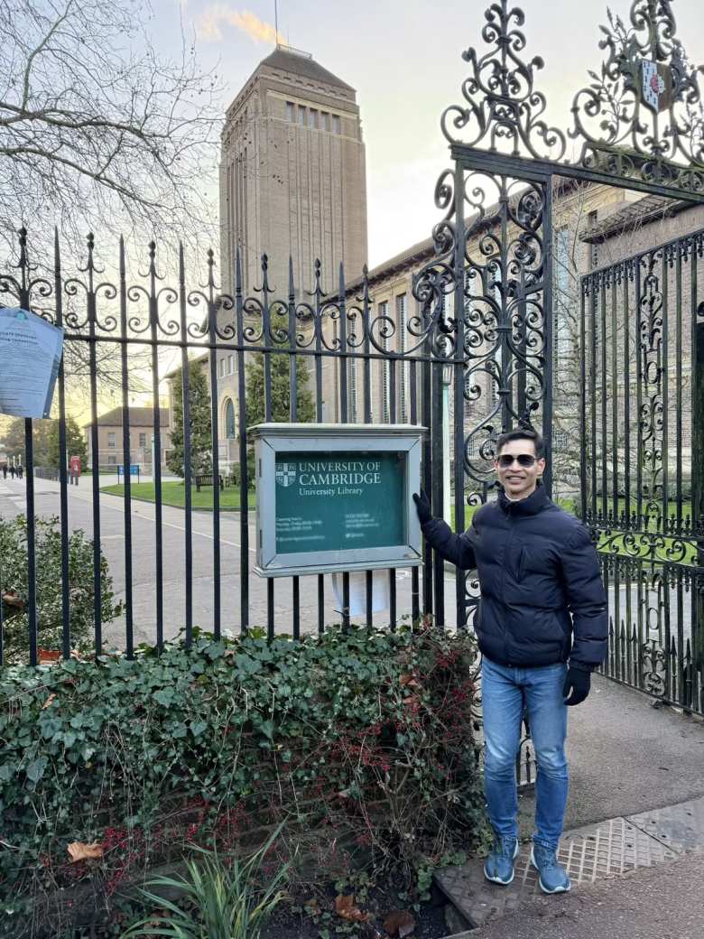 Felix next to a University of Cambridge sign. The University Library is just beyond this gate.