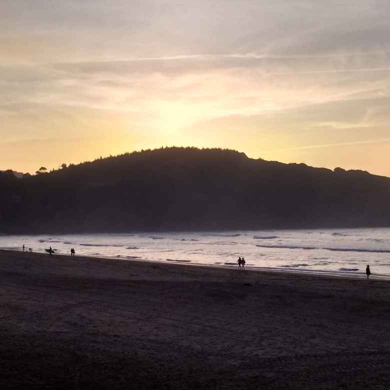 Surfers along the beach of La Arena, Spain.