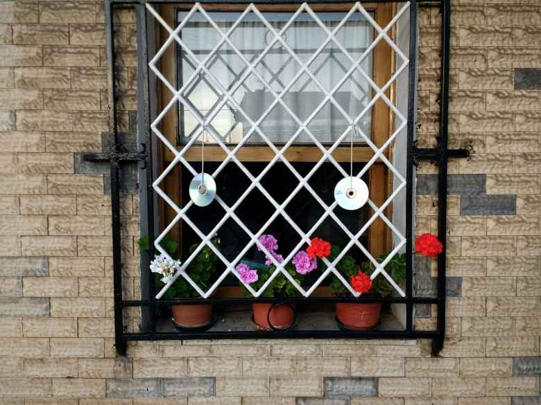 CDs upcycled as art and flowers in a window in a town west of Santander, Spain.