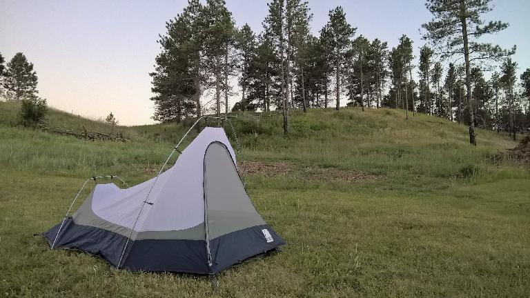 White and blue Sierra Designs Clip Flashlight CD tent, grass, pine trees, Chadron State Park.