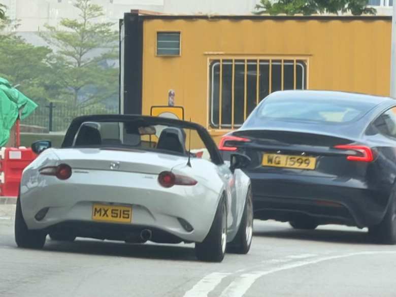 A white fourth-generation Mazda Miata with its top down in Hong Kong.