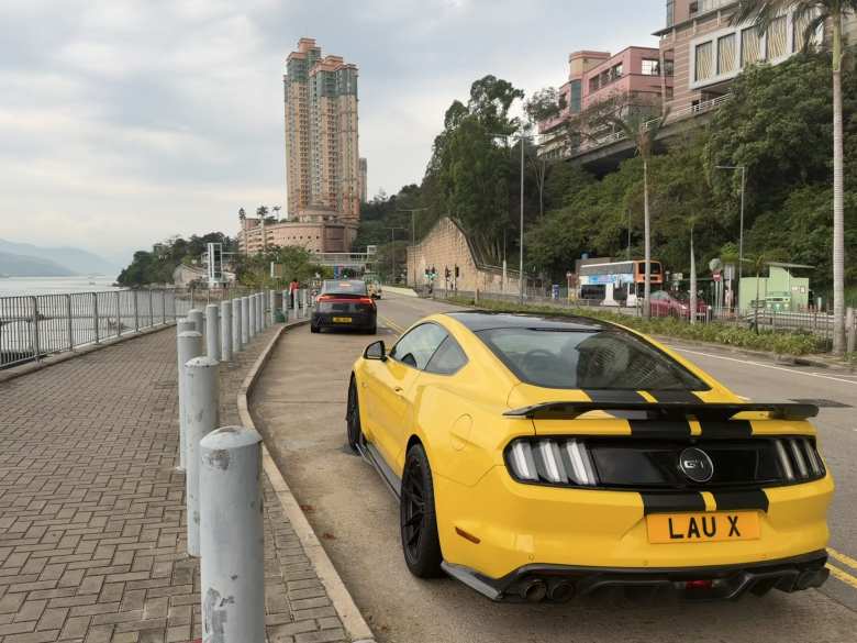A yellow sixth-generation Ford Mustang with black racing stripes and rear spoiler.