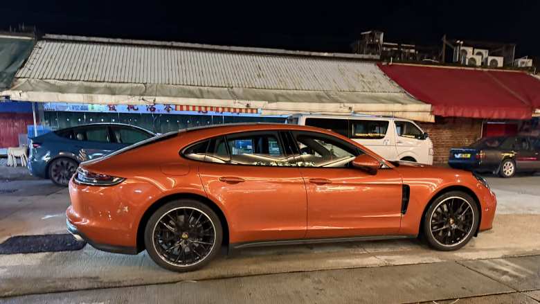 An orange Porsche Panamera near a fish market in Hong Kong.