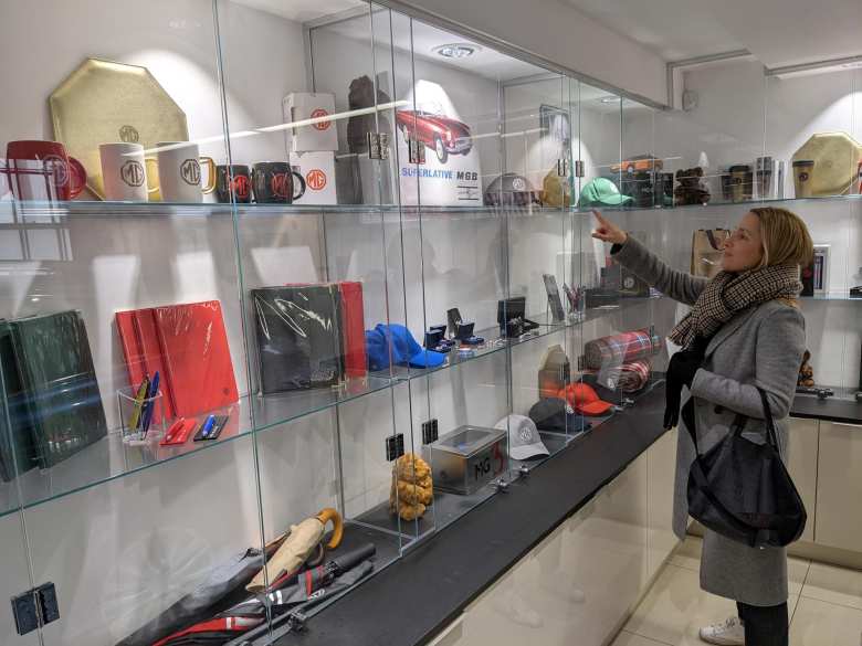 Andrea pointing to a Superlative MGB sign in the memorabilia section of an MG store near Piccadilly Circus in London.