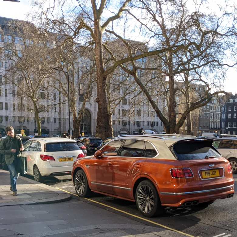 A two-tone brown/white Bentley Bentayga SUV outside the Bentley dealership near Hyde Park.